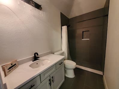 Finished bathroom with dark tile shower and gray vanity